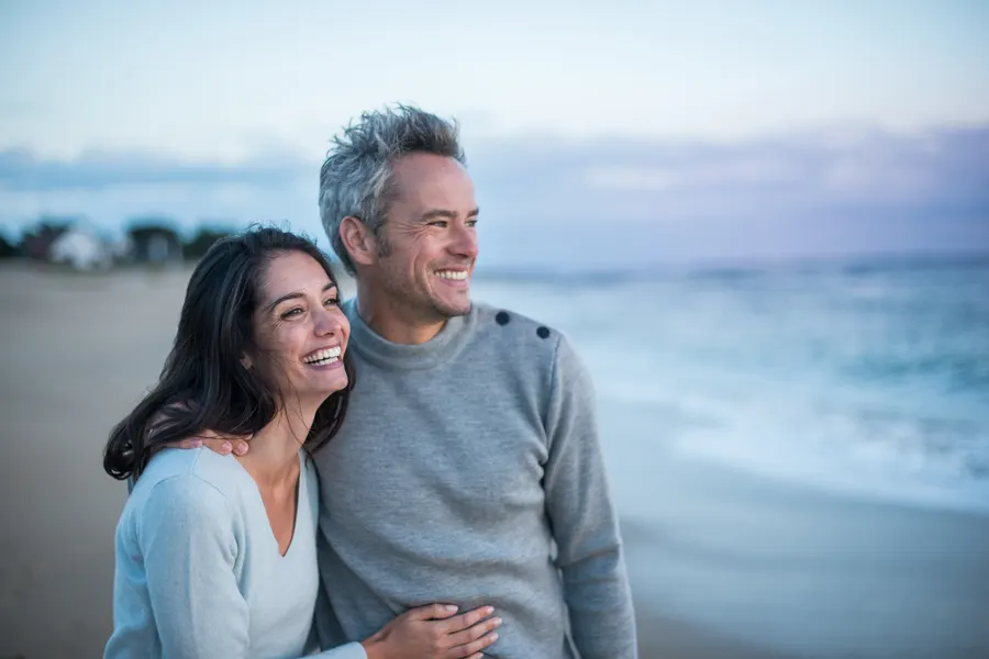 A smiling couple in their fifties on a beach