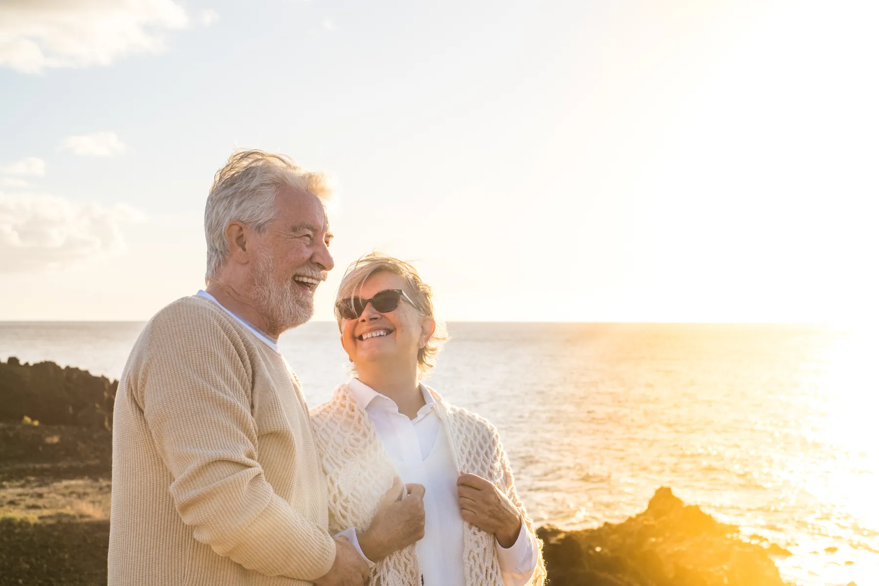An older couple laughing by the sea