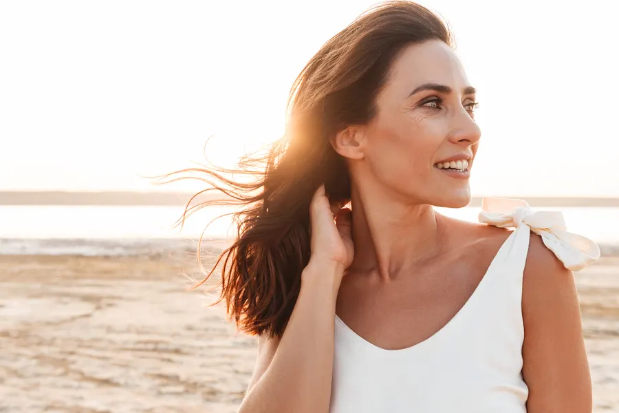 A woman on a beach with her hand in her hair