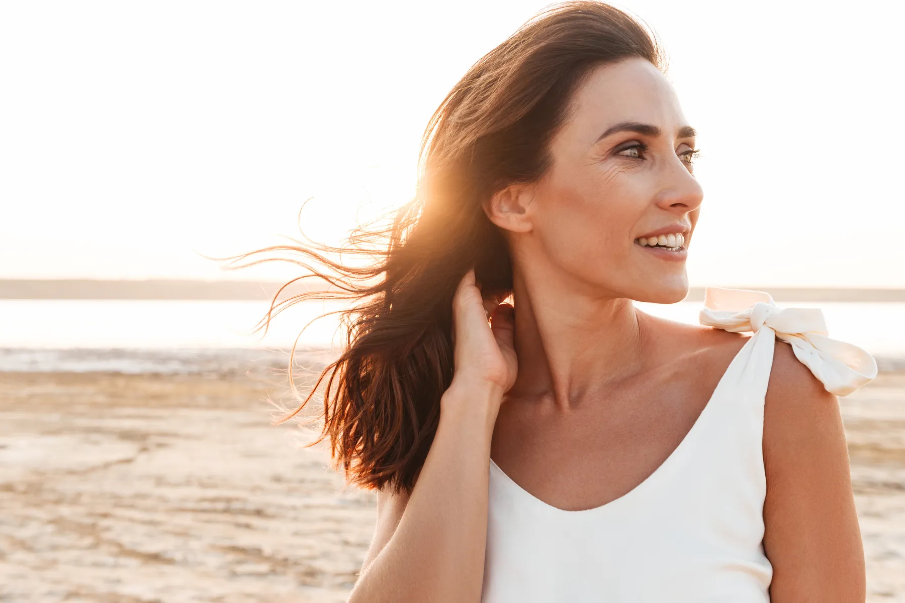 A woman on a beach with her hand in her hair