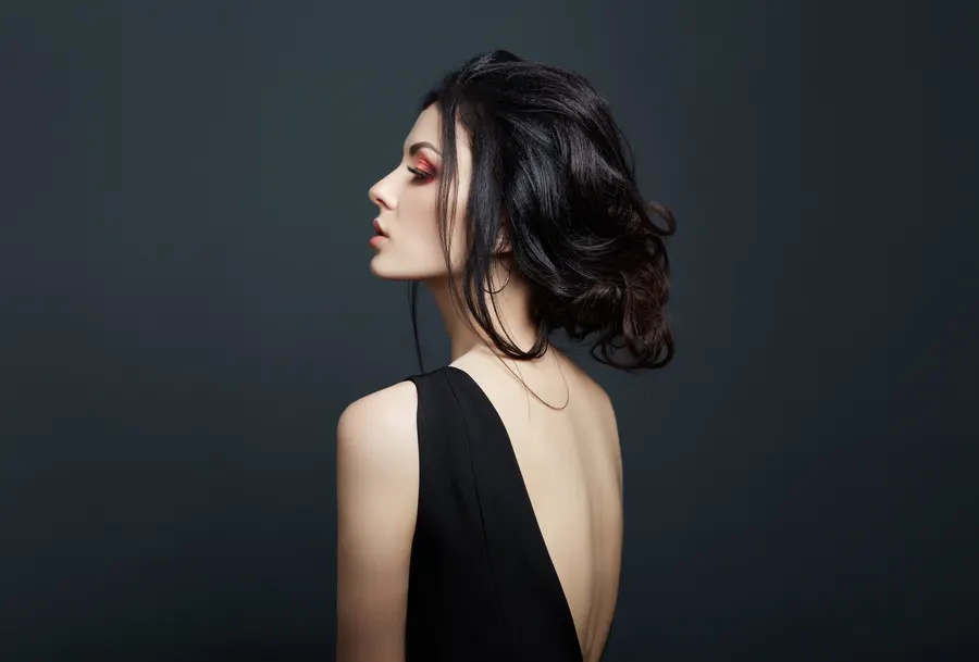 A woman in a black dress seen from behind, her neck and shoulders