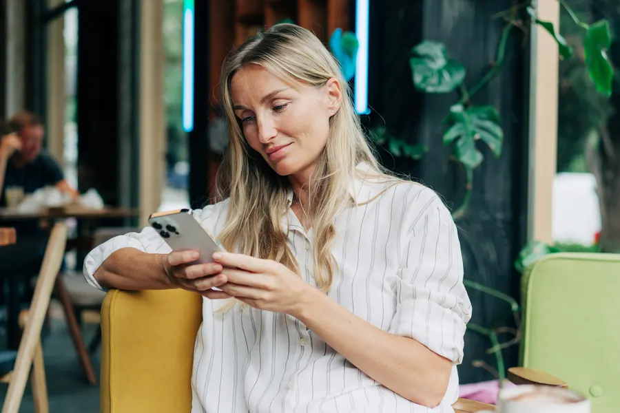A blonde woman reading her phone in a cafe