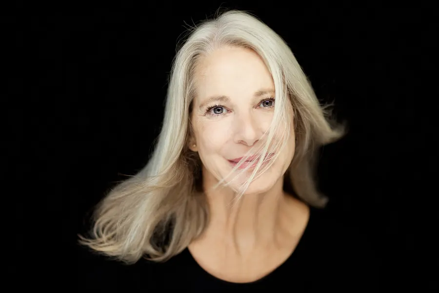 A woman with long silver hair on a black background