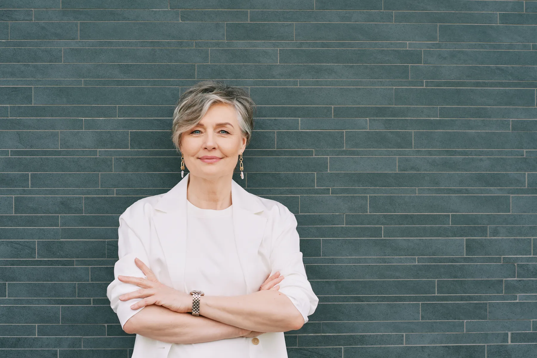 A woman in her sixties in a white shirt, arms crossed